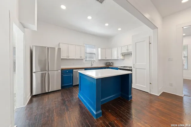 a kitchen with stainless steel appliances granite countertop a refrigerator a sink dishwasher and a stove with wooden floors