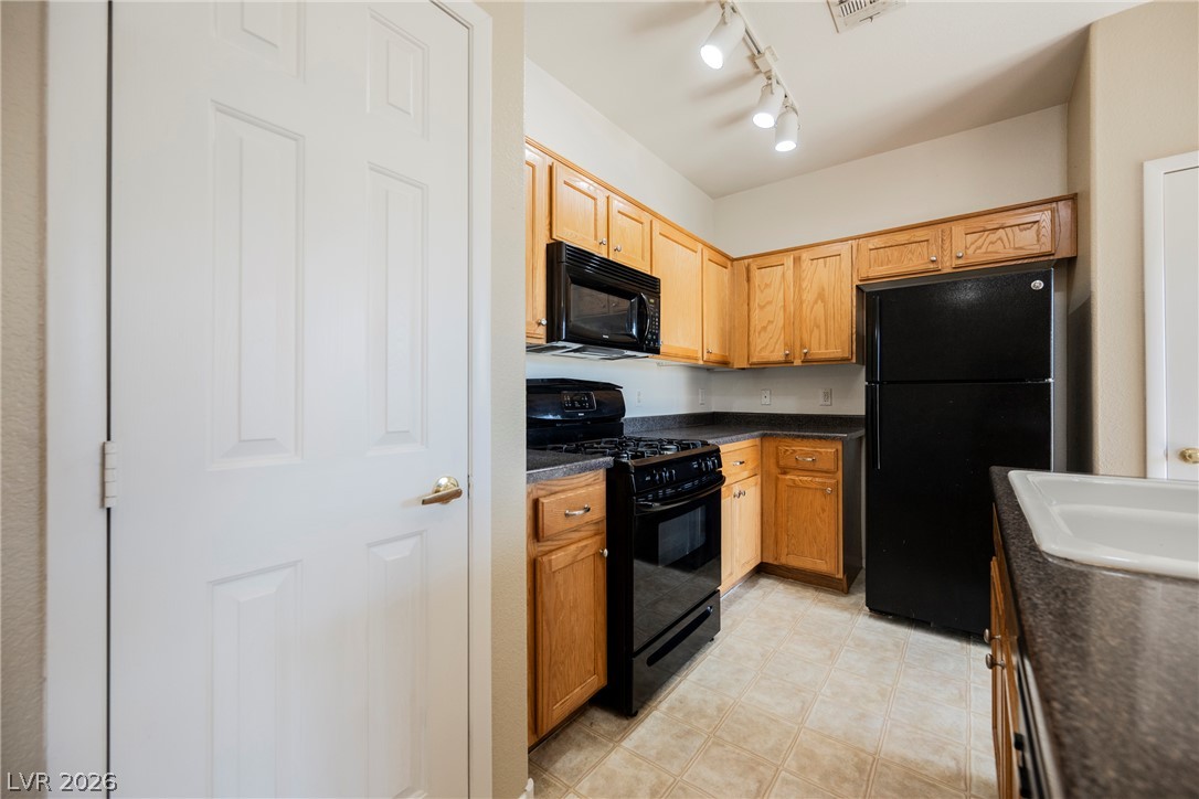 6320 Snap Ridge Street, Unit 201 North Las Vegas, NV 89081 - Photo 22 of 56 A compact kitchen offering light wood cabinetry and a suite of black appliances.