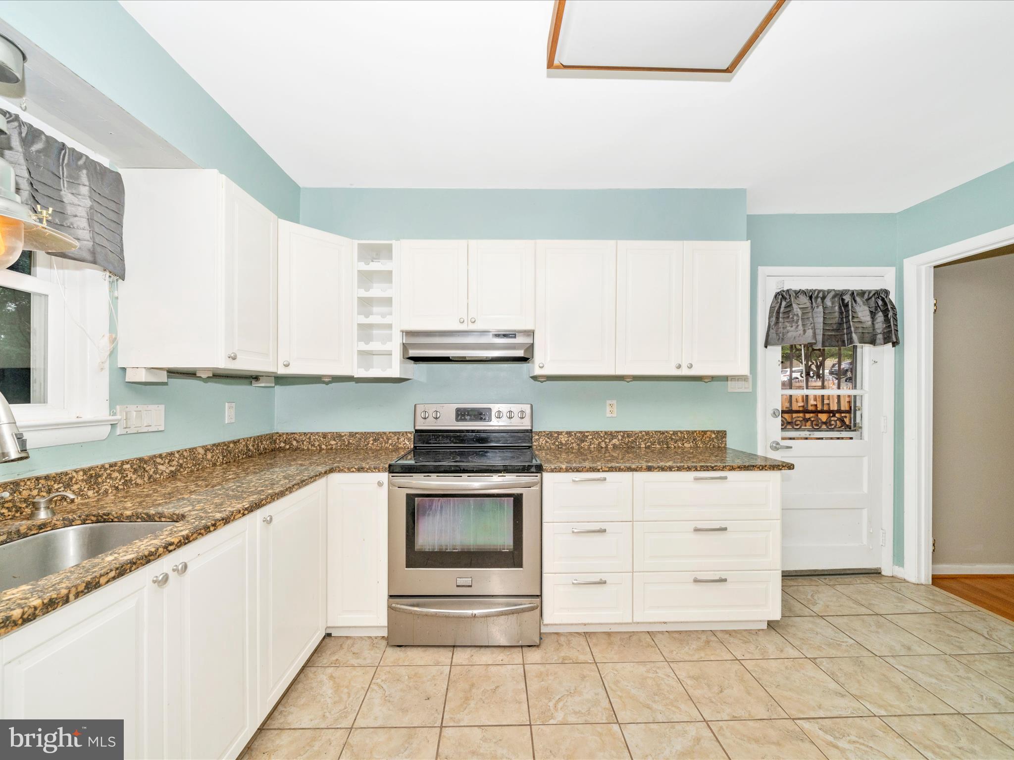7019 Fitzpatrick Drive Laurel, MD 20707 - Photo 15 of 59 a kitchen with granite countertop a stove top oven microwave and cabinets