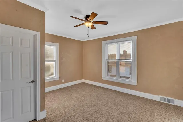 an empty room with ceiling fan and windows