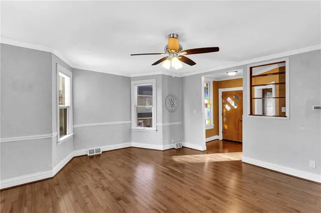 a view of empty room with wooden floor and fan