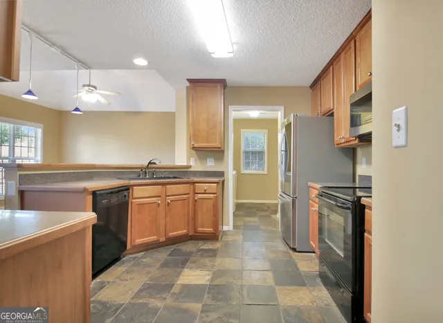 a kitchen with stainless steel appliances granite countertop a refrigerator stove and sink