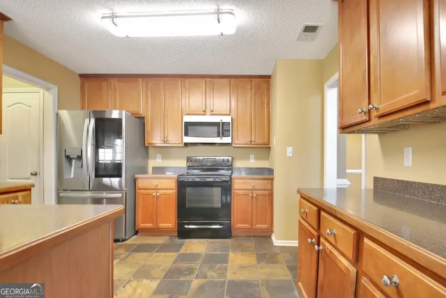 a kitchen with granite countertop a refrigerator and a stove top oven