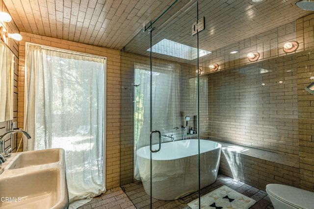 a bathroom with a tub a sink and glass door shower