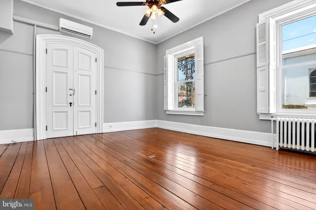 a view of an empty room with wooden floor and a window