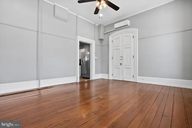 an empty room with wooden floor cabinet and windows