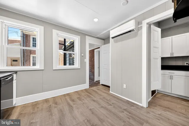 a view of an empty room with a window and a kitchen