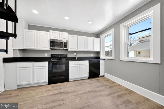 a kitchen with granite countertop a stove a sink and a microwave