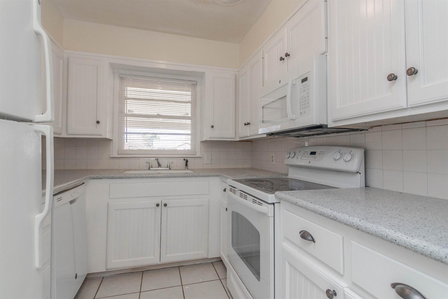 3221 33rd Street, Unit A Lubbock, TX 79410 - Photo 6 of 11 a kitchen with white cabinets appliances a sink and dishwasher