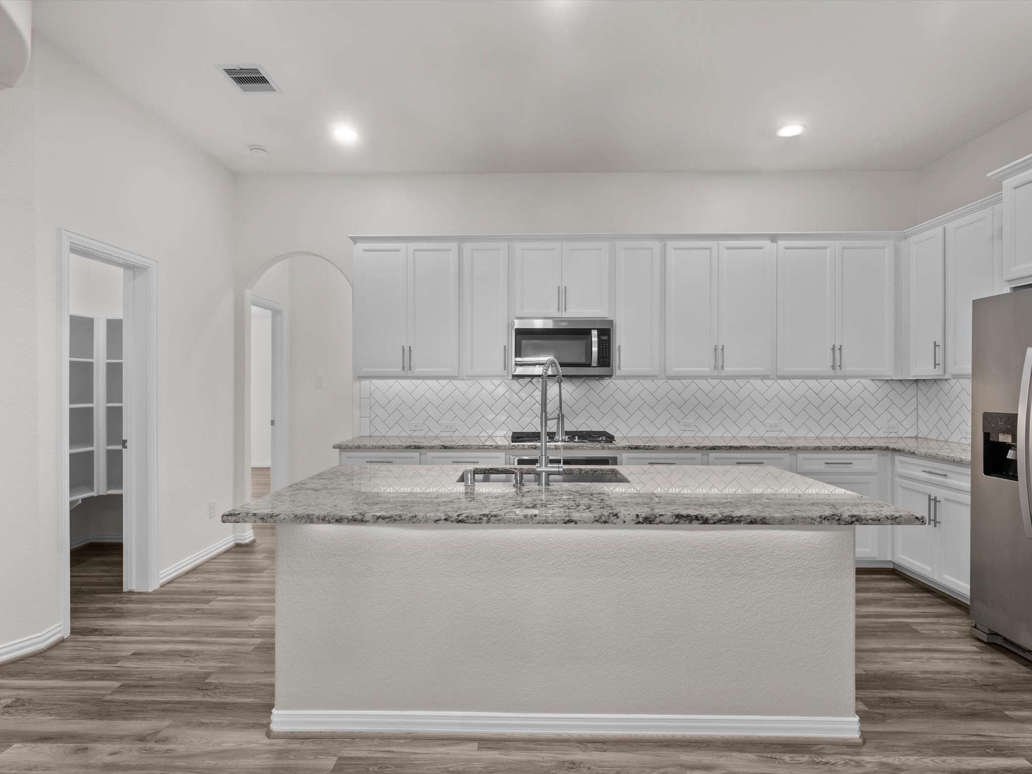 4746 Misty Ranch Drive Spring, TX 77386 - Photo 13 of 49 The kitchen features a herringbone tile backsplash, granite countertops, stainless steel appliances, a gas range, and a spacious island with room for bar seating. Walk In Pantry.