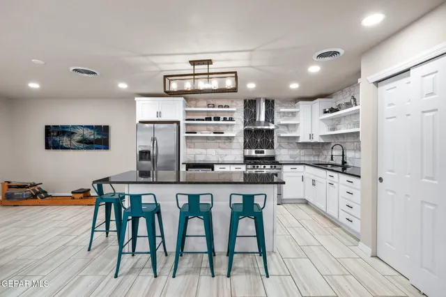 a kitchen with stainless steel appliances a table chairs refrigerator and cabinets