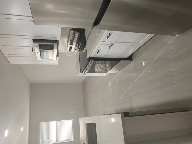 183 Mimosa Road Dale, TX 78616 - Photo 4 of 11 Modern kitchen featuring stainless steel appliances, white cabinetry with dark hardware, a smooth-top range, and light-toned tile flooring