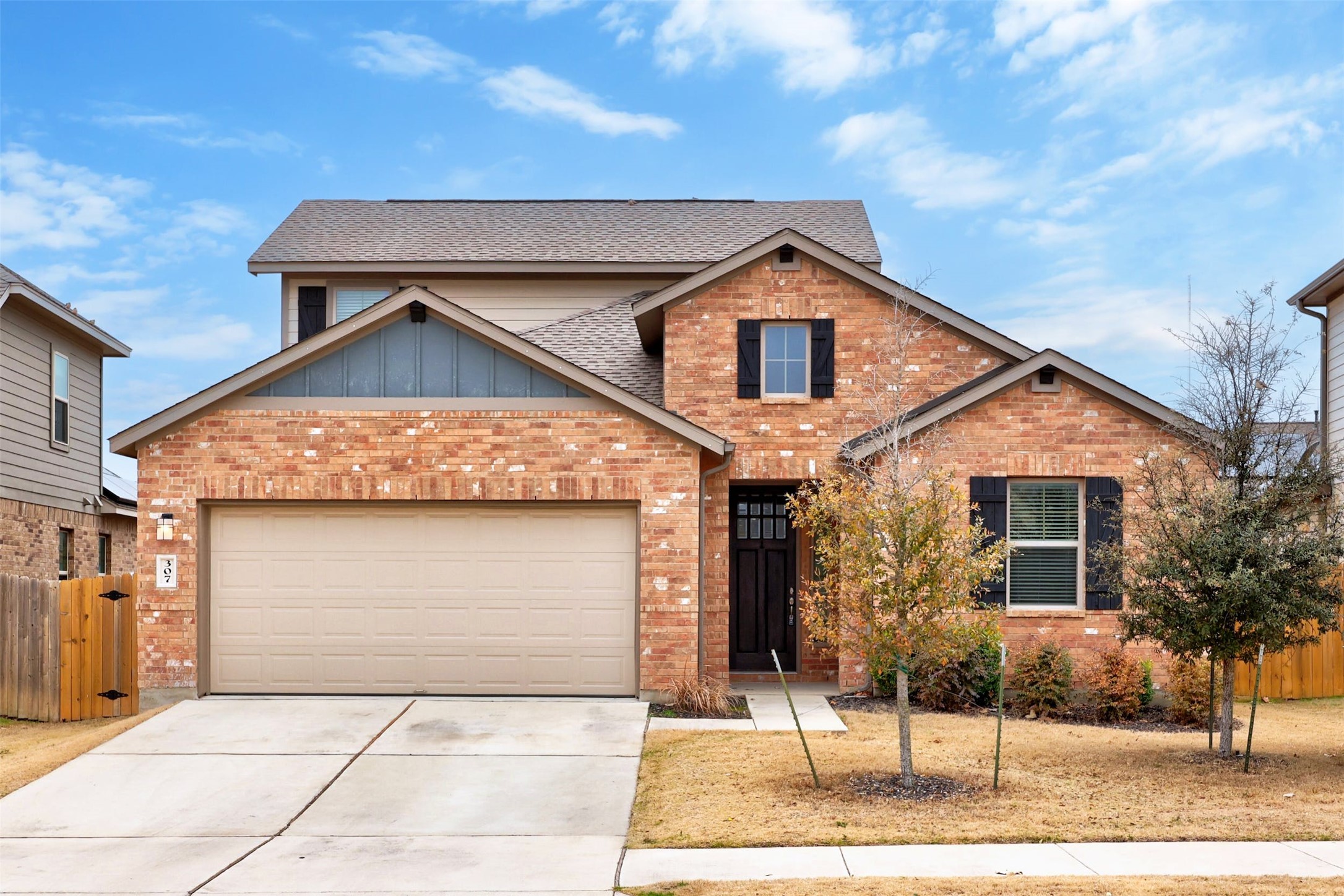 A classic brick exterior with dark shutters and an attached garage creates inviting curb appeal.