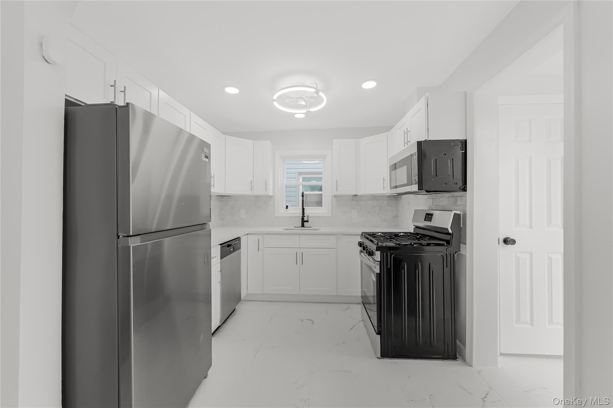 173-43 103rd Road Queens, NY 11433 - Photo 8 of 43 White cabinetry with brushed nickel hardware, stainless steel appliances, white countertops, white tile backsplash, and a modern ceiling fixture