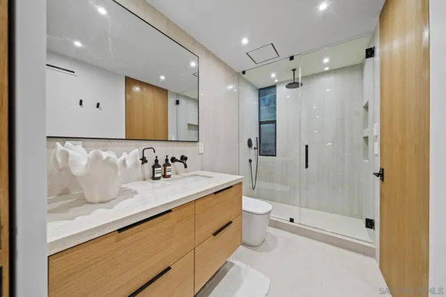 a bathroom with a bathtub shower sink mirror and toilet