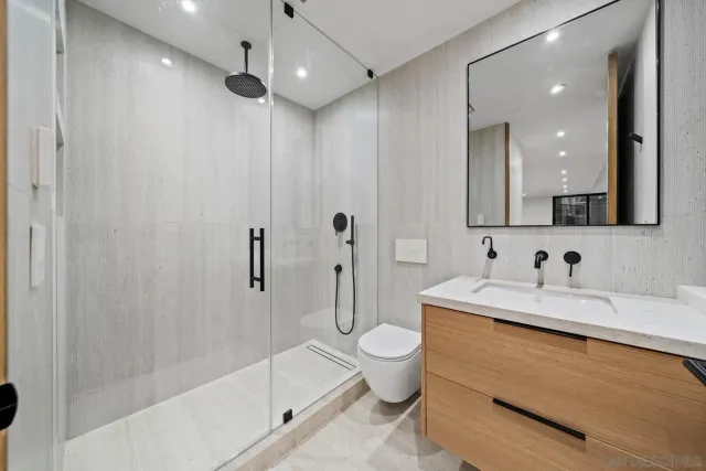 a spacious bedroom with a bed and a flat tv screen on dresser