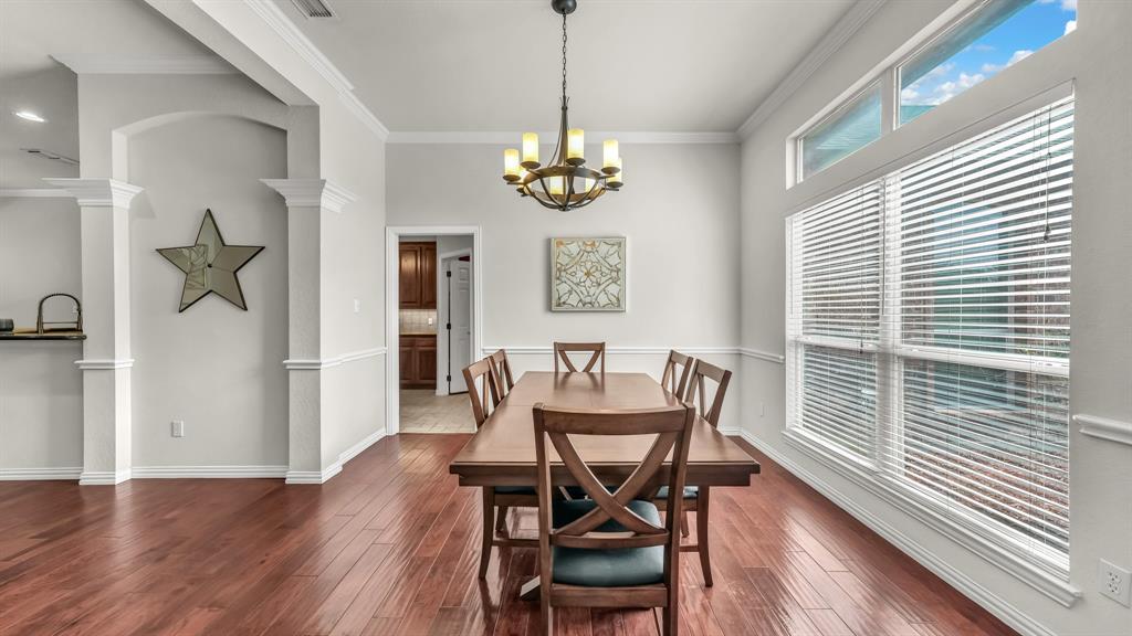 203 Mockingbird Lane Aledo, TX 76008 - Photo 8 of 37 Formal dining area featuring rich wood-finish flooring, a contemporary chandelier, and extensive natural light from large windows with transom panels
