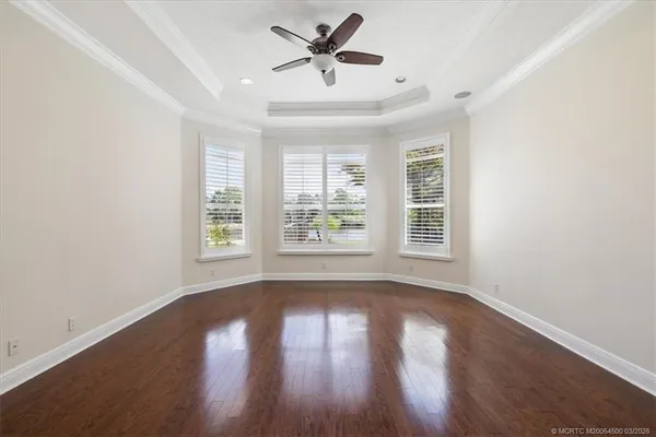 a view of empty room with wooden floor and fan