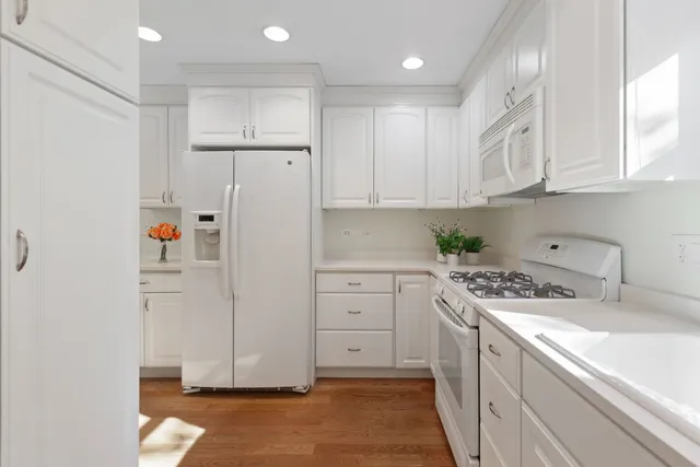 a kitchen with white cabinets and white appliances