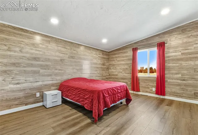 a spacious bedroom with a bed and wooden floor