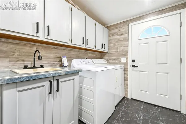 a utility room with granite countertop a sink and a white cabinets