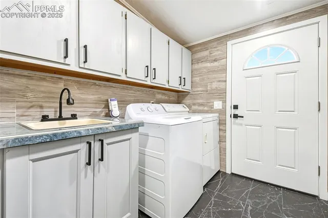a utility room with granite countertop a sink and a white cabinets