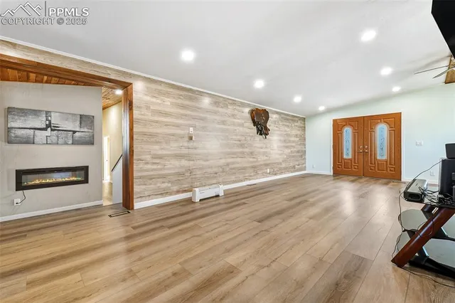 a view of an empty room with wooden floor and a fireplace