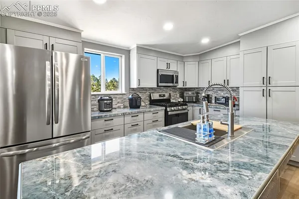 a kitchen with stainless steel appliances granite countertop a refrigerator sink and stove
