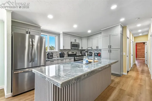 a kitchen with stainless steel appliances granite countertop a refrigerator a sink and a stove