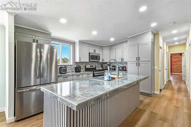 a kitchen with stainless steel appliances granite countertop a refrigerator a sink and a stove