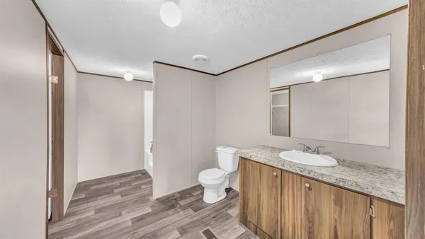 a bathroom with a granite countertop sink a toilet and a mirror