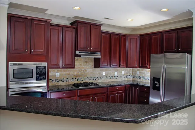 a kitchen with stainless steel appliances granite countertop wooden cabinets a refrigerator and a sink