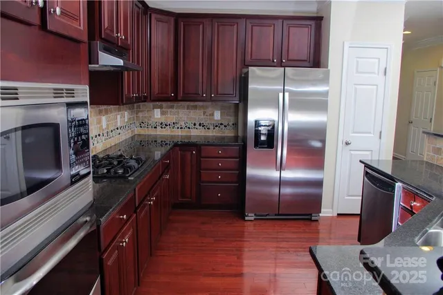 a kitchen with stainless steel appliances granite countertop a stove a refrigerator and a sink