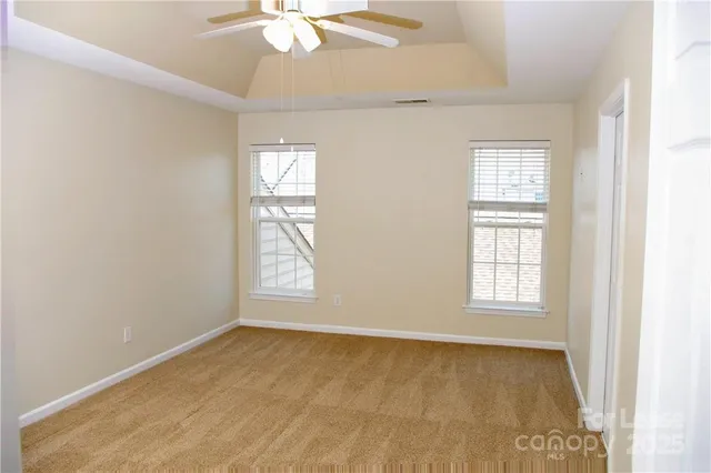 an empty room with windows and fan