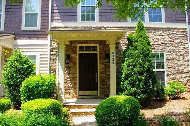 a view of a house with potted plants and a bench