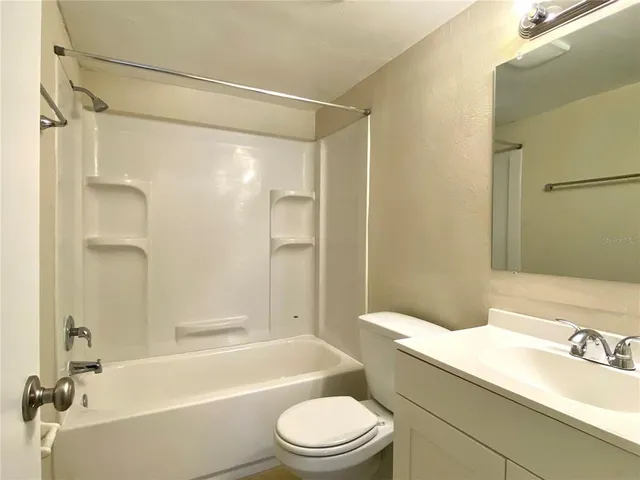 a bathroom with a granite countertop bathtub shower sink mirror vanity and toilet