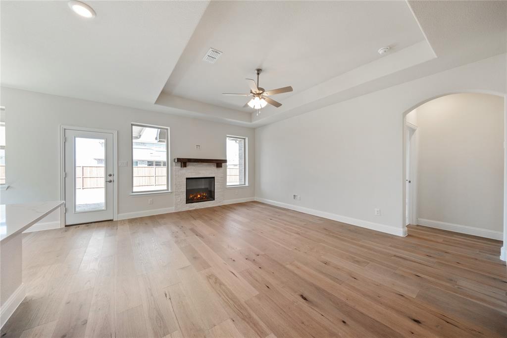 116 Old Glory Lane Forney, TX 75126 - Photo 9 of 23 an empty room with wooden floor fireplace and windows