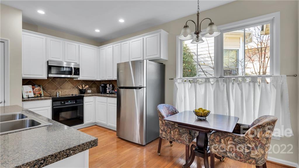 3221 Fifth Baxter Crossing Fort Mill, SC 29708 - Photo 13 of 30 a kitchen with stainless steel appliances granite countertop a refrigerator a sink dishwasher a stove and a dining table with wooden floor