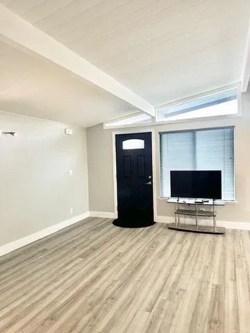 a view of livingroom with wooden floor and a flat screen tv