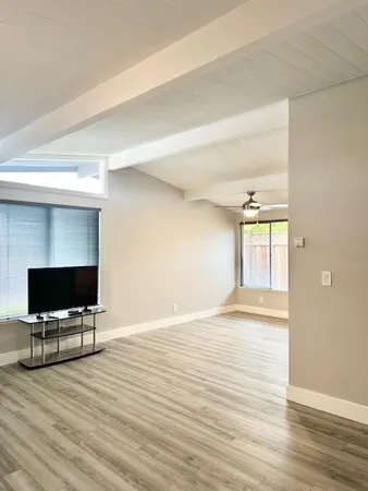 a view of empty room with wooden floor and window