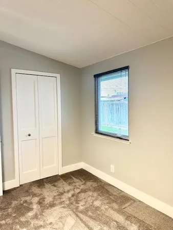 a view of an empty room with window and closet