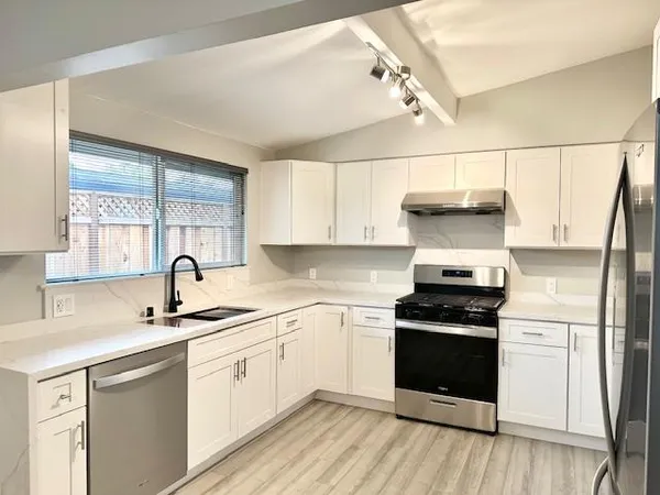 a kitchen with a sink appliances cabinets and a counter top space