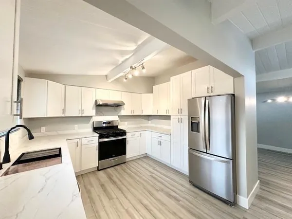 a kitchen with a refrigerator a stove top oven a sink and white cabinets