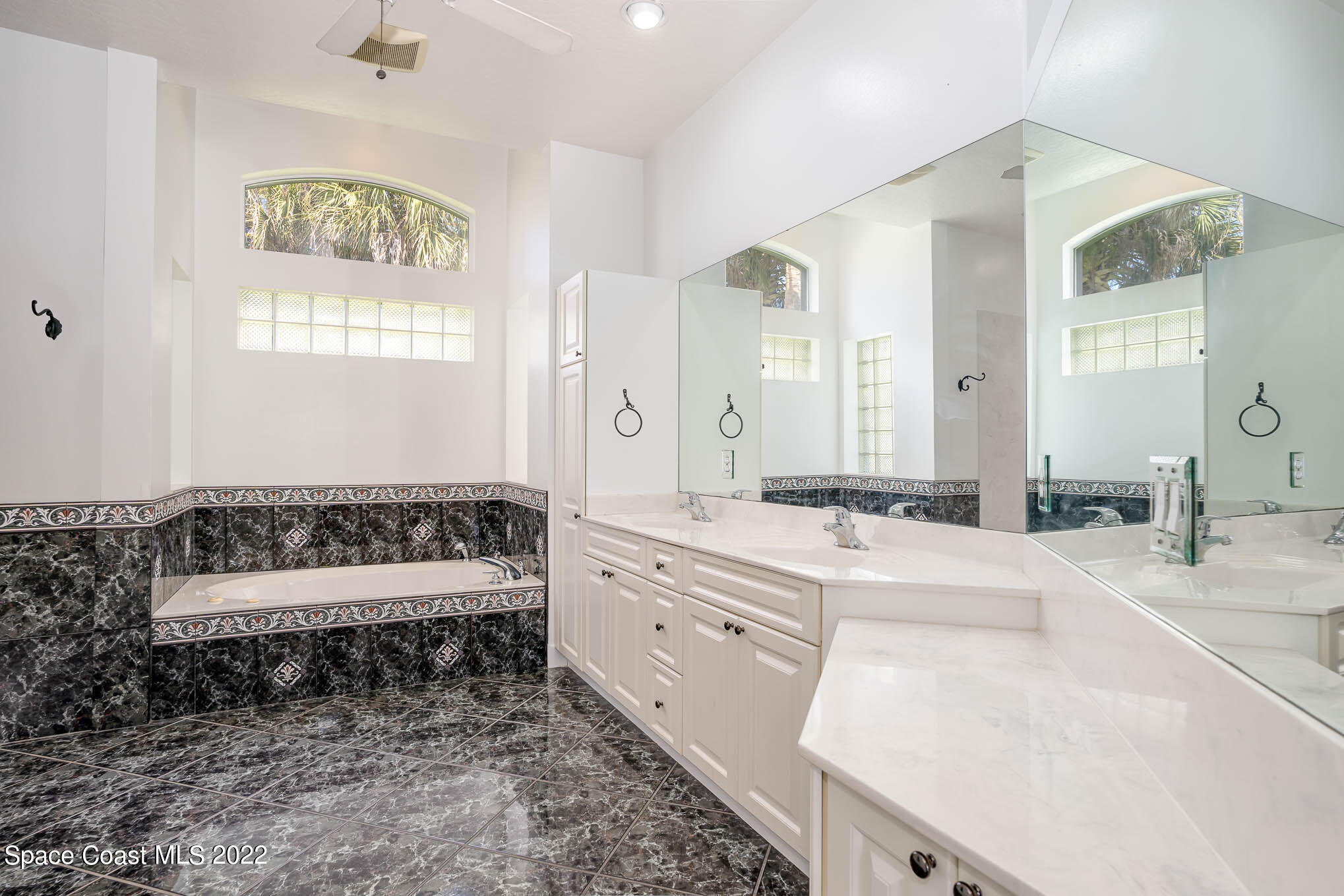 3920 Postridge Trail Melbourne, FL 32934 - Photo 15 of 52 a bathroom with a double vanity sink a mirror a bathtub and window