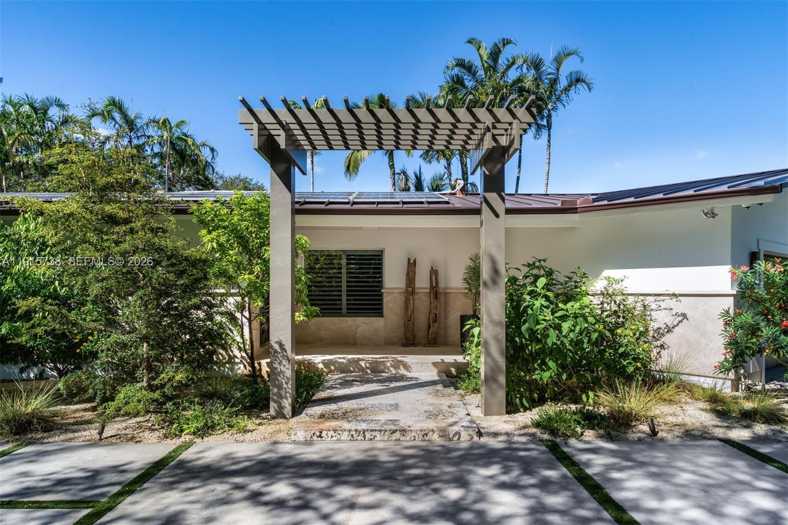 12050 Moss Ranch Road Pinecrest, FL 33156 - Photo 2 of 33 front view of a house with potted plants and a yard