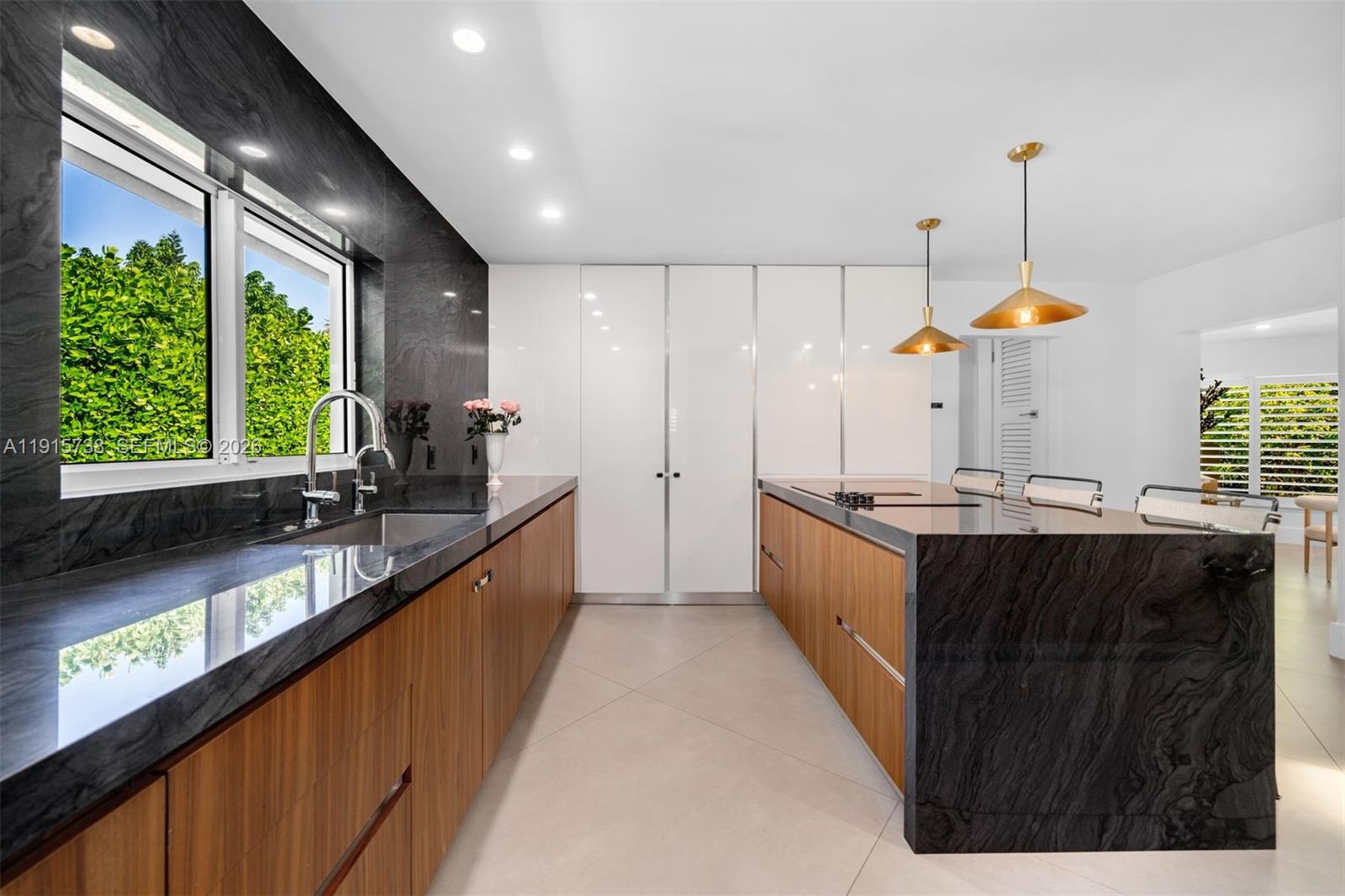 12050 Moss Ranch Road Pinecrest, FL 33156 - Photo 8 of 33 a large kitchen with a large counter top a sink a window and stainless steel appliances