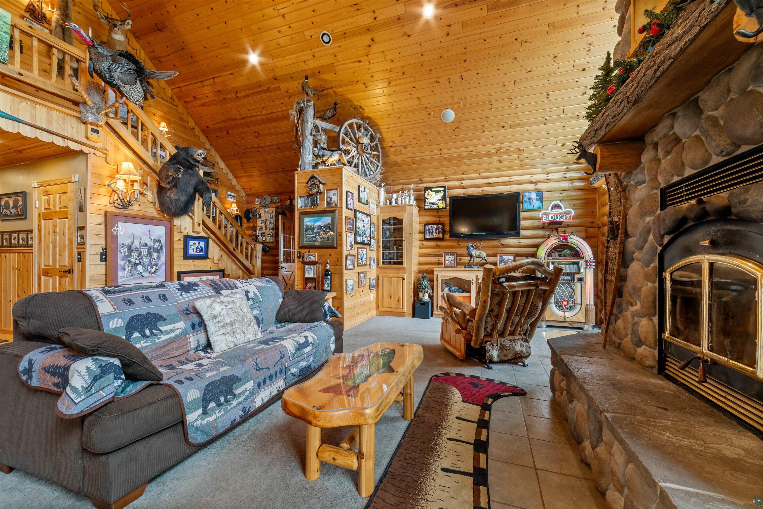 11911 East Rowe Road Lake Nebagamon, WI 54849 - Photo 49 of 61 Living area featuring a stone fireplace with a stone hearth, wood-paneled walls, and a wood-paneled vaulted ceiling