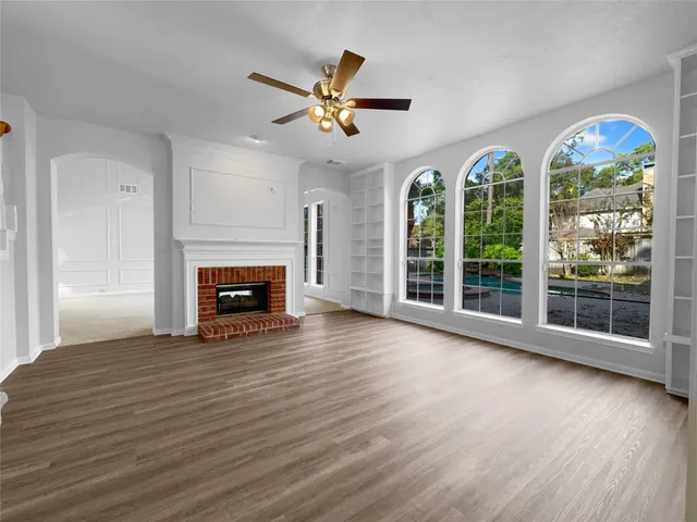 a view of an empty room with wooden floor fireplace and a window