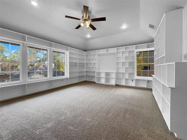 an empty room with windows and ceiling fan