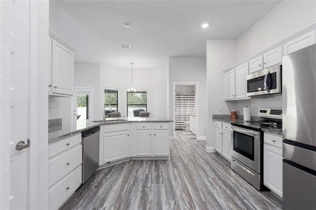 a kitchen with a sink wooden floor and stainless steel appliances
